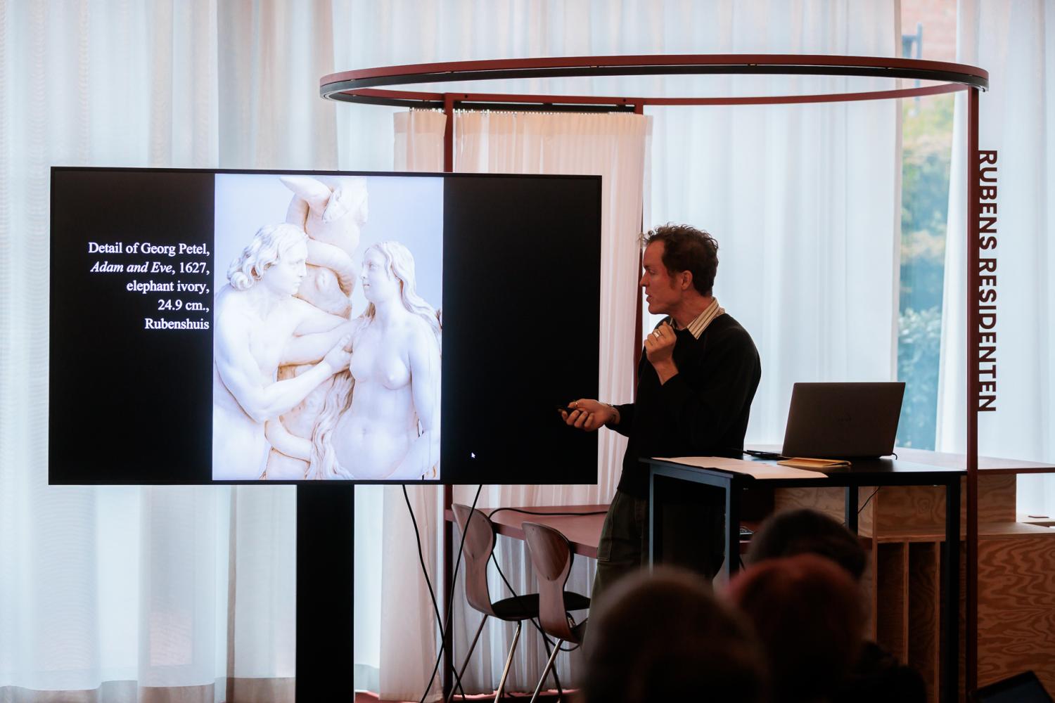 Visiting researcher John White toont Adam en Eva van Georg Petel tijdens een presentatie